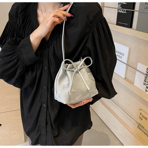 Détail d'un sac seau métallisé argenté avec cordon à nœud et fine bandoulière