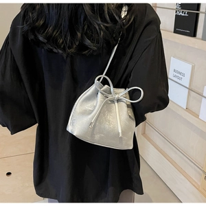 Sac seau argenté avec grand nœud et texture métallique porté par un mannequin au dos