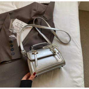Détail du sac argenté métallisé avec nœud en perles et boucle étoile sur blazer marron