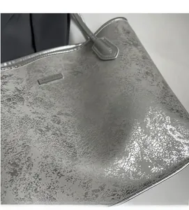 Detailed macro view of silver tote bag showing metallic texture and logo plate