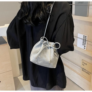 Détail du sac seau argenté avec texture métallique et décoration de grand nœud