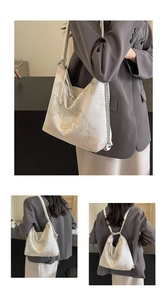 Close-up of Chinese embroidery patterns and metal chain detail on the beige bag