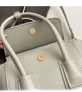 Close-up of gold magnetic clasp and fine stitching on a sage green bucket bag