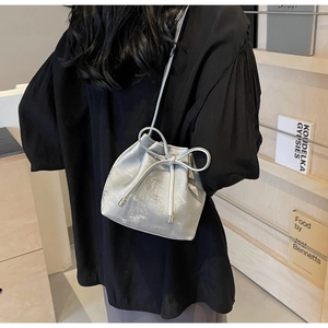 Sac seau argenté avec fermeture à cordon et nœud élégant porté par un mannequin