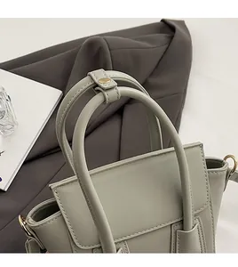 Detailed close-up of the grey leather handbag with comfortable handle and metal D-ring