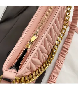 Détail du sac en cuir plissé rose avec fermeture éclair dorée et finitions métalliques