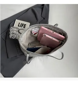 Top view showing the spacious interior of the silver tote bag with tablet and phone