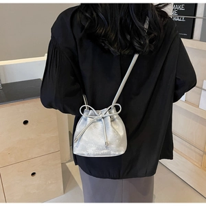 Détail du sac seau argenté à cordon avec nœud porté en bandoulière pour femme