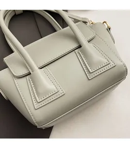 Detail of a sage green bucket bag showing precise stitching and golden metal hardware