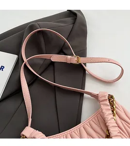 Détail d'une bandoulière réglable avec boucle dorée sur un sac plissé rose tendre
