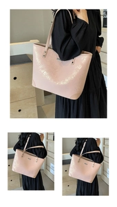 Detail of pink glossy patent leather tote bag featuring a silver metal logo and crackle texture