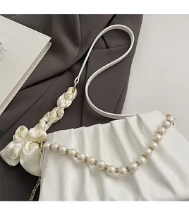 Detail of white pleated cloud bag featuring pearl chain and silk knotted handle decoration