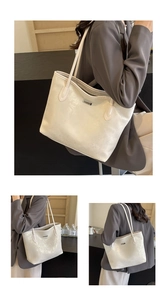 Detail view of large white pearlized tote bag with metal tag and zipper on shoulder strap