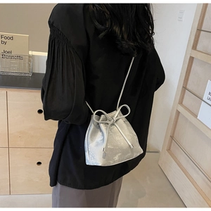 Détail du sac seau argenté métallisé avec grand nœud coulissant et bandoulière fine