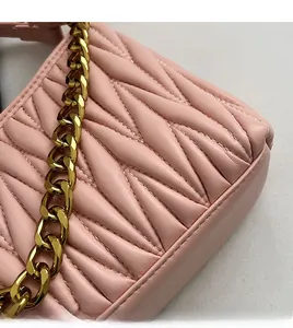 Détail de la texture cuir rose plissé matelassé et de la chaîne dorée premium