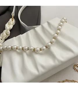 Detailed close-up of white pleated cloud bag featuring elegant pearl chain and gold hardware