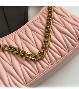 Détail de la texture en cuir matelassé rose avec une élégante chaîne en métal doré