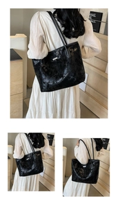 Detail of black tote bag with glossy wrinkled texture and silver metal brand plaque