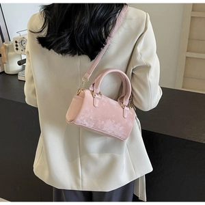 Detail of pink velvet Boston bag with gold hardware shown on a shoulder