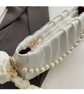 Detailed macro of smooth gold zipper and red inner lining on white ruched cloud bag