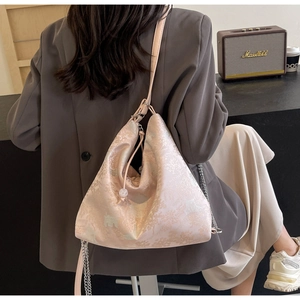 Detail of elegant floral jacquard fabric with pearl drawstring on a pink crossbody bag
