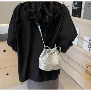 Sac seau argenté avec texture métallique lavée et détail de cordon à nœud élégant