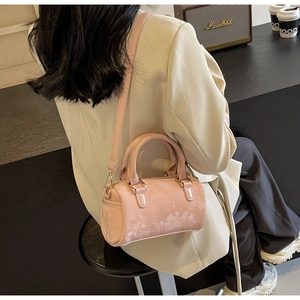 Pale pink Boston bag with textured leather and gold hardware shown in a lifestyle scene