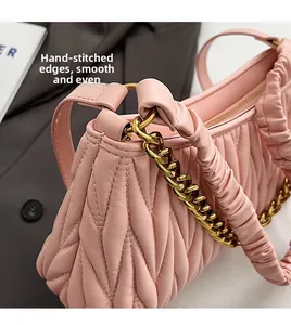 Gros plan du sac plissé rose montrant les coutures détaillées et la chaîne dorée