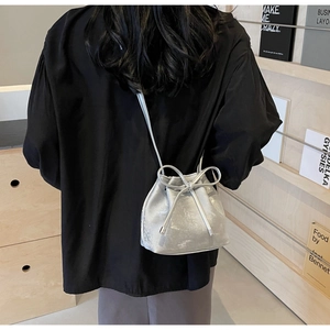 Sac seau argenté avec cordon de serrage et nœud porté en bandoulière par un mannequin