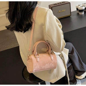 Chic pink leather barrel bag styled with a beige blazer for an elegant urban look