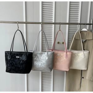 Detail of four metallic tote bags in black, silver, pink, and beige with crackle texture
