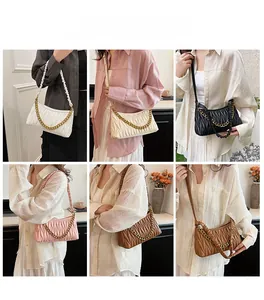 Modèles portant des sacs à bandoulière plissés avec des chaînes dorées élégantes
