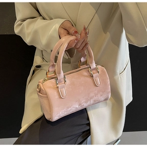 Detail view of pink suede Boston bag with gold metal hardware and rounded handles