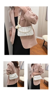 Detail of pleated shoulder bag with white pearl chain and elegant silk ribbon strap