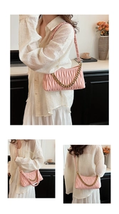 Détail d'un sac à bandoulière plissé rose avec texture verticale et chaîne dorée