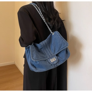 Detail of washed denim tote bag with silver chain strap shown worn on a female model