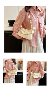 Detail of cream white pleated shoulder bag featuring pearl chain and silk bow accent