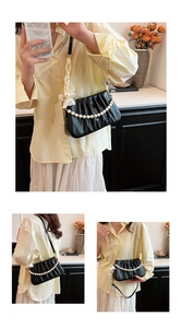 Detail of black pleated shoulder bag featuring pearl chain and white silk bow charm