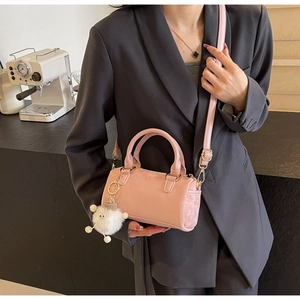 Pink Boston bag with white plush lamb charm and gold metal zipper shown on shoulder