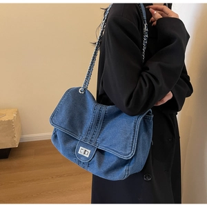 Detail showing the denim fabric texture and silver chain strap on a blue tote bag