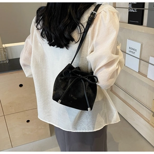 Détail du sac seau noir à cordon avec nœud décoratif et texture mate et lisse