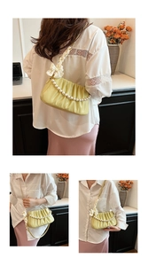 Detail view of yellow pleated cloud bag with pearl chain and silk bow shoulder strap