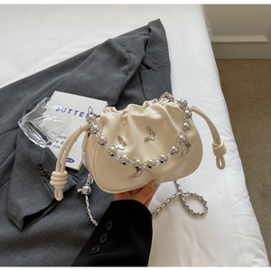 Detail of cream pleated cloud bag with silver butterfly charms and beaded handle