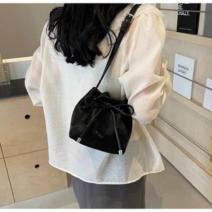 Détail d'un sac seau noir avec nœud coulissant et finitions métalliques argentées chic