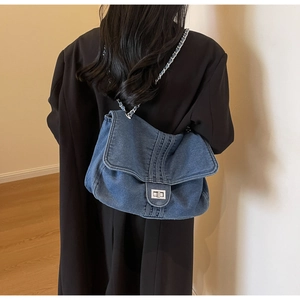 Detail of blue washed denim shoulder bag with silver chain strap and metal twist lock closure
