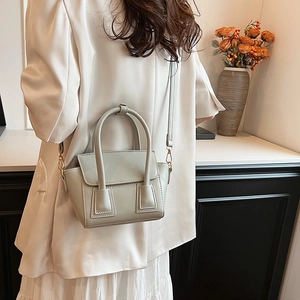 Elegant light greyish-green structured bucket bag with top handles shown on model