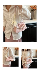 Detail showing pink pleated PU leather shoulder bag with pearl chain and silk bow ornament