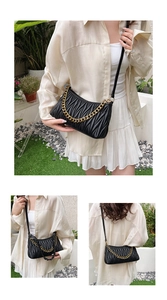 Détail d'un sac bandoulière plissé noir avec une chaîne dorée et une sangle en cuir