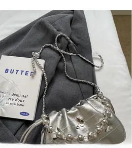 Detail of silver metallic pleated bag with butterfly charms and long beaded chain strap