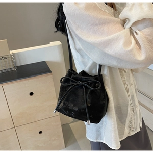 Détail d'un sac seau noir texturé montrant le cordon de serrage et les embouts en argent